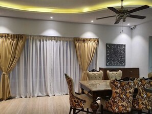 A dining room with a table and chairs, a ceiling fan, and curtains.