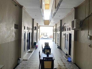 A corridor with doors on both sides, a tiled floor, and a table with chairs in the center. - Stylish Delux Twin Stay With Free Wifi and Parking (Palangkaraya)