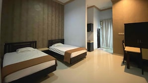 Ein Hotelzimmer mit zwei Betten, einem Flachbildfernseher und einem durch eine geöffnete Tür einsehbaren Badezimmer.