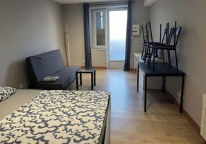 Hotellihuone, jossa on sänky, sohva, pieni pöytä, työpöytä tuoleineen ja näkymä ulos.