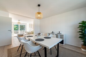 A modern dining area with a white table, black chairs, and a hanging light fixture. - Apartment "Onjito" with Shared Garden, Balcony, and Wi-Fi (Saarbrücken)