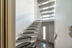 A modern staircase with white railings and grey steps, leading to a door with a window. - Apartment "Onjito" with Shared Garden, Balcony, and Wi-Fi (Saarbrücken)