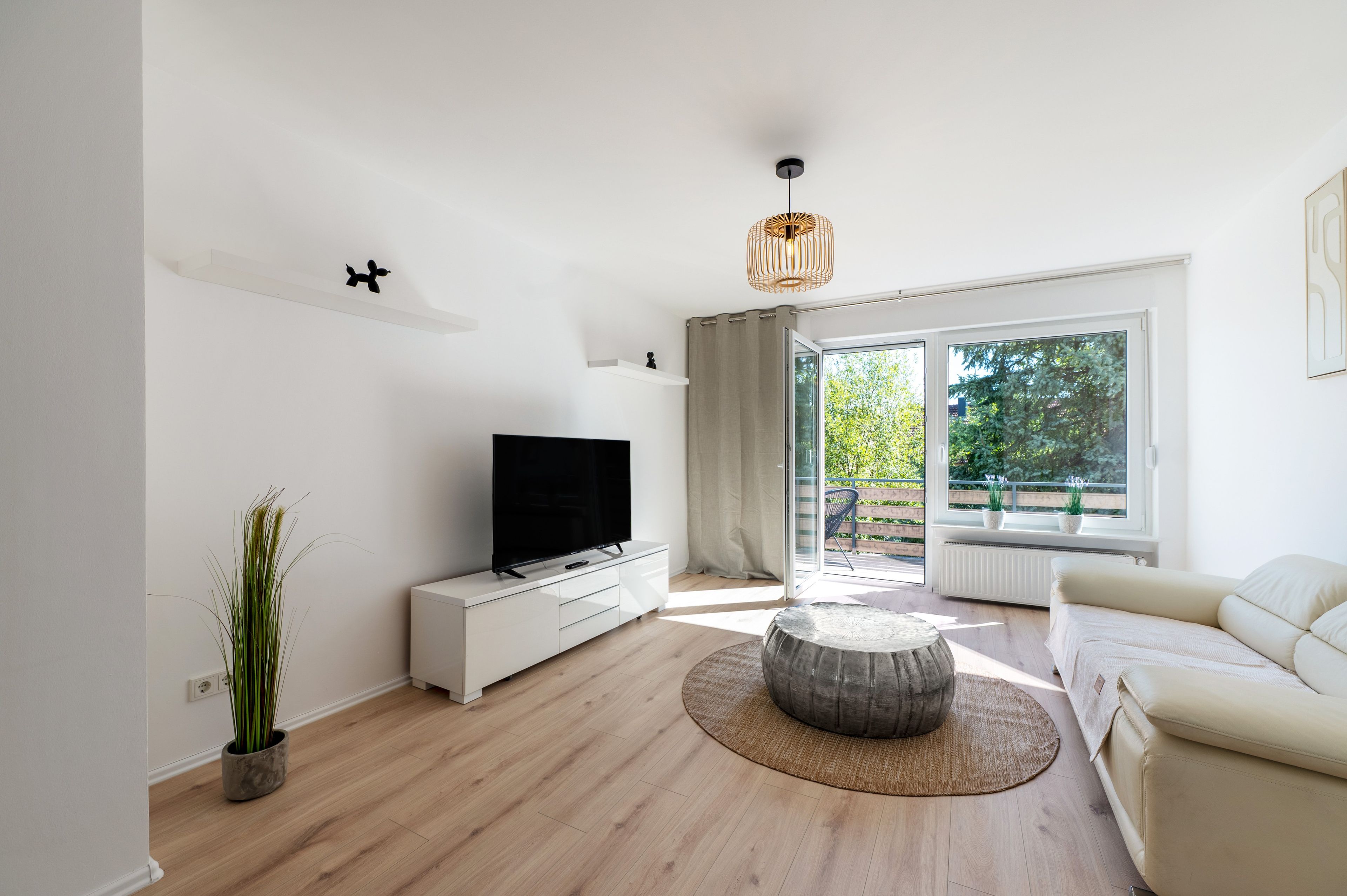 Un soggiorno moderno con una televisione a schermo piatto, un tavolino rotondo e un divano.