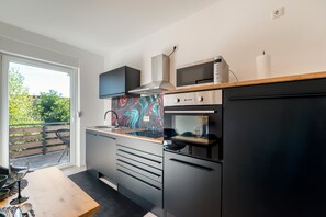 Eine moderne Küche mit Einbauofen, Mikrowelle und großem Fenster.