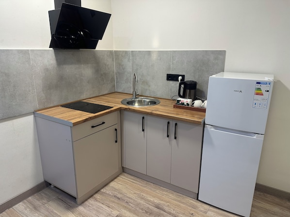 A compact kitchen with a sink, a coffee maker, and a refrigerator.
