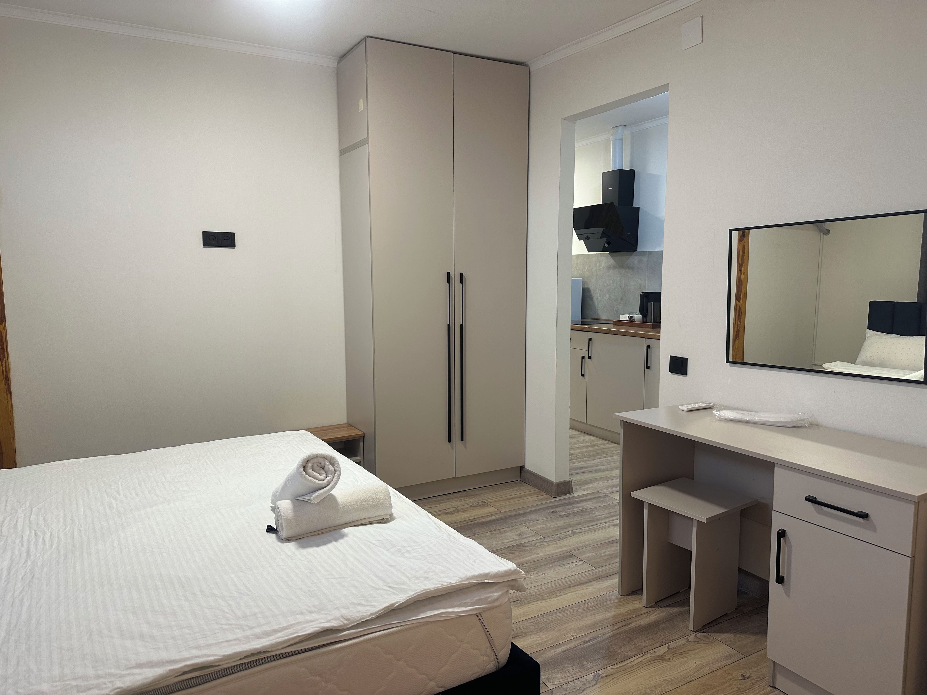 Un dormitorio con cama, mesita de noche, armario, escritorio y espejo.