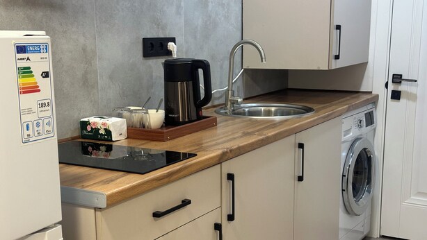 Una cocina moderna con lavadora integrada, cafetera y hervidor sobre la encimera.