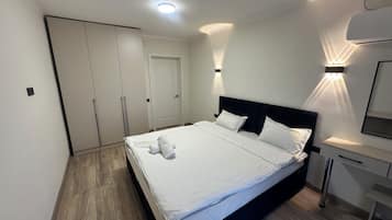 Un dormitorio con cama, mesitas de noche, armario y una lámpara de pared.