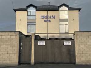 Edifício com placa indicando 'DREAM HOTEL' e entrada com portão.