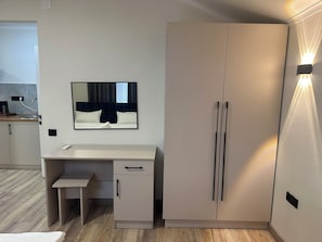 Quarto moderno com cama, mesa de cabeceira, guarda-roupa e espelho.