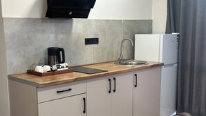 Una cocina compacta con encimera de madera, cafetera, fregadero y refrigerador blanco.
