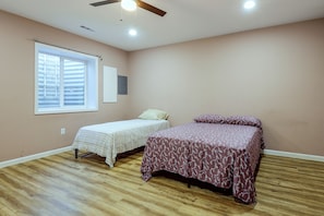 A bedroom with two beds, a window with blinds, a ceiling fan, and a light switch on the wall. - Ashburn Extended Stay w/ Shared Yard (Ashburn)
