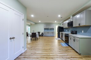 A modern kitchen with white cabinets, a black microwave, and a blue-tiled backsplash. - Ashburn Extended Stay w/ Shared Yard (Ashburn)