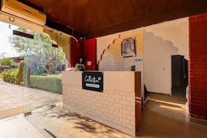 A reception area with a reception desk, a sign indicating it's a company-serviced collection point, and a fire exit sign.