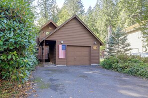 Ein zweistöckiges Haus mit Garage, einer amerikanischen Flagge und einem Steinsschornstein.