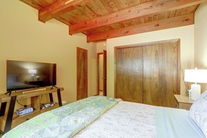 Ein Schlafzimmer mit einem Bett, einem Fernseher auf einem Holztisch, einem Kleiderschrank und einem Nachttisch mit einer Lampe.