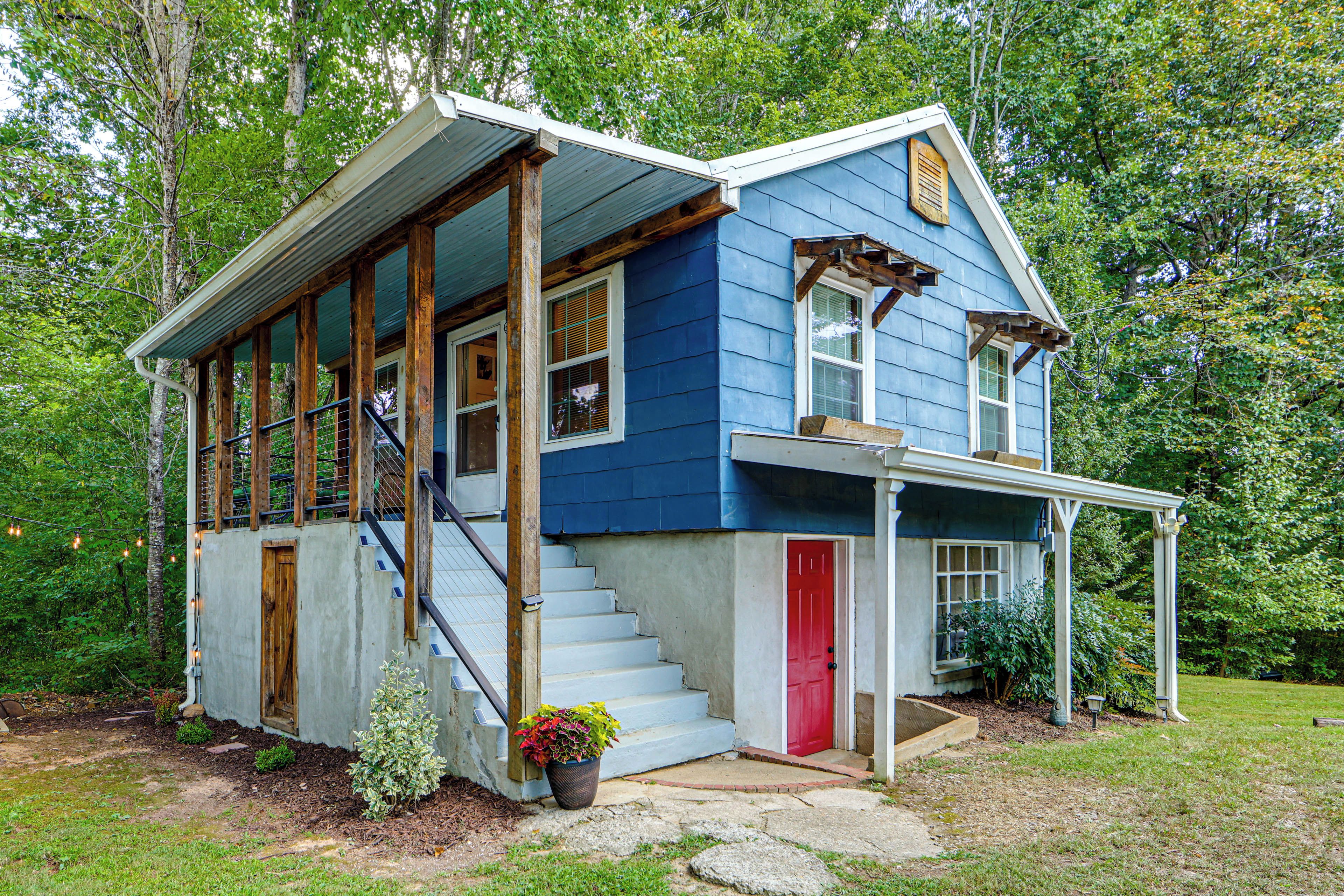 A two-story house with a porch, wooden staircase, and a red door.