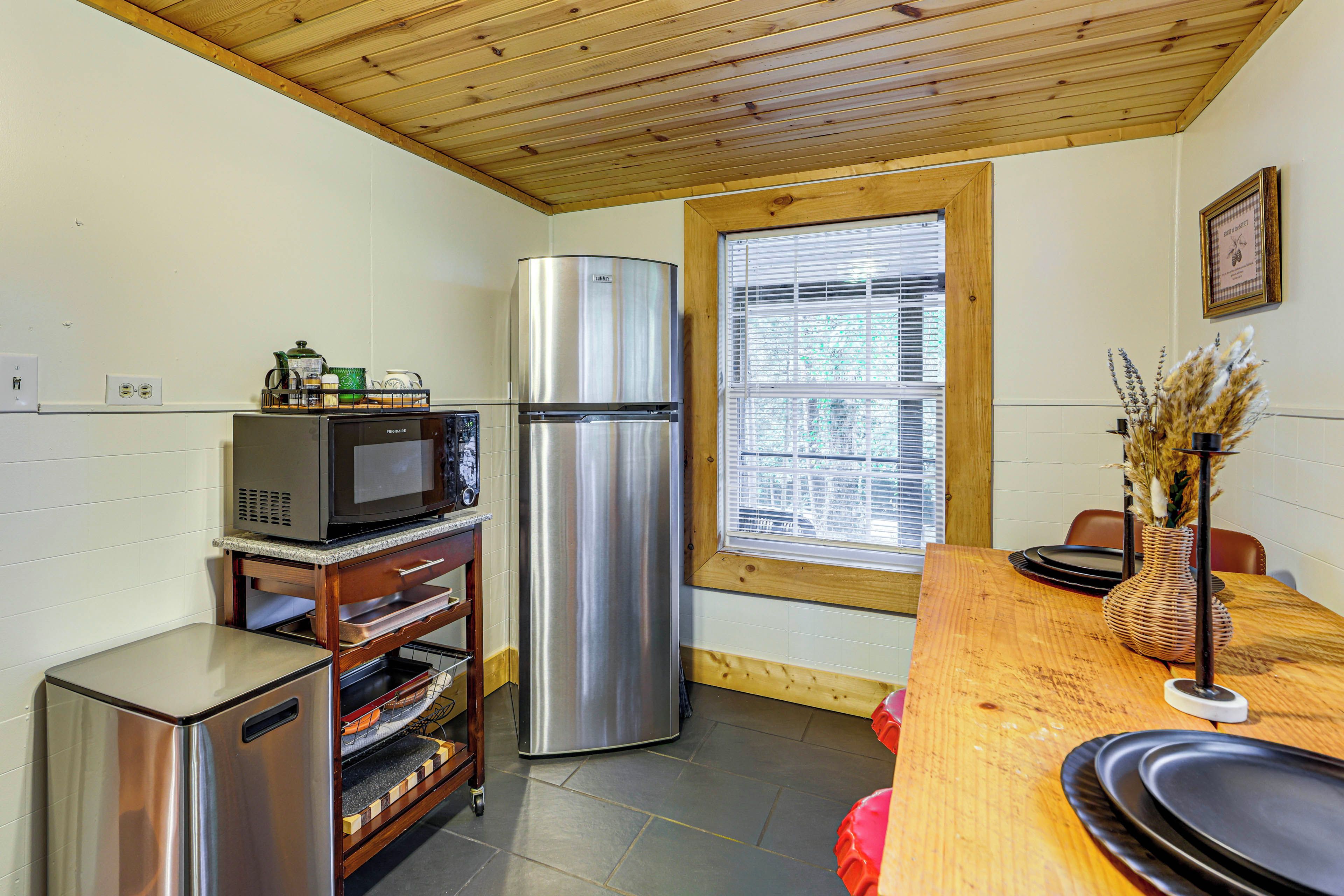 A compact kitchen with a refrigerator, microwave, and a small oven on a wooden countertop.