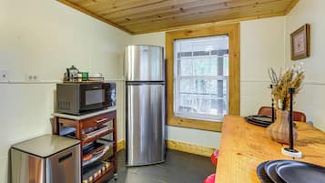 A compact kitchen with a refrigerator, microwave, and a small oven on a wooden countertop.