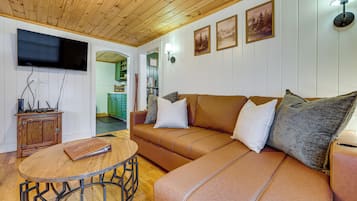 A cozy living room with a brown leather sofa, a wooden coffee table, and a flat-screen TV mounted on the wall.