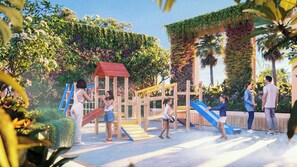 Un parque infantil con estructuras para escalar y toboganes, rodeado de abundante vegetación y palmeras.
