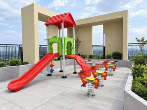 Ein Kinderspielbereich mit Rutsche, Klettergerüst und schwingenden Tierfiguren an Federn.