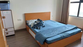 A bedroom with a wooden bed, a small cabinet, and a window.