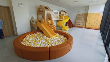 A play area with a ball pit, slides, and wooden play structures.