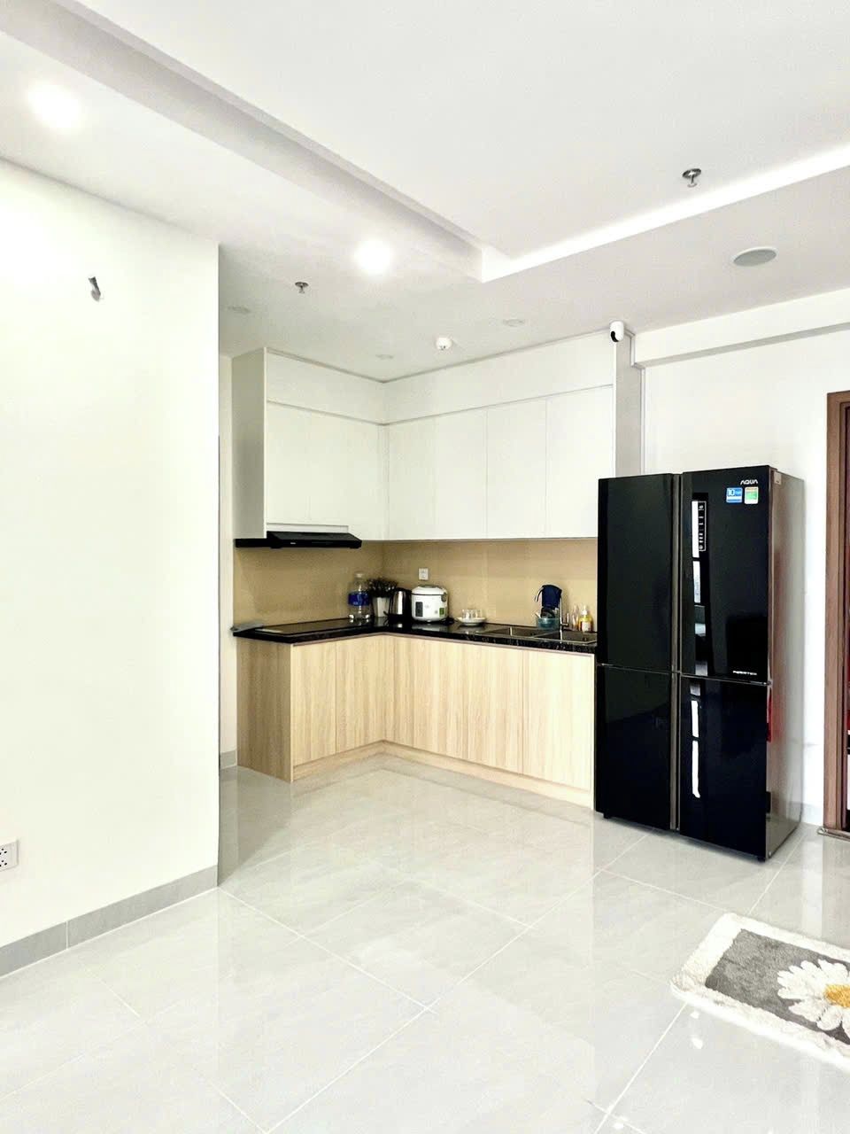A modern kitchen with white cabinets, a black refrigerator, and a tiled floor.