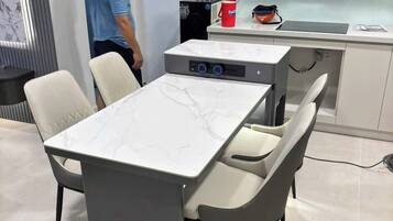 A modern kitchen with white cabinets, a marble countertop, and a built-in stove.