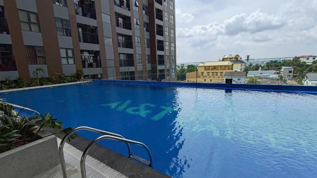 Piscina com escada de metal, rodeada por um edifício com várias varandas.