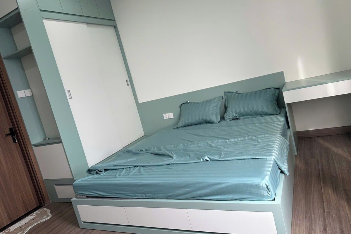 Quarto individual com guarda-roupa embutido, porta e chão de madeira.