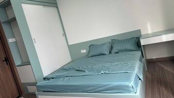 Une chambre individuelle avec un lit simple, une armoire intégrée, une porte et un plancher en bois.