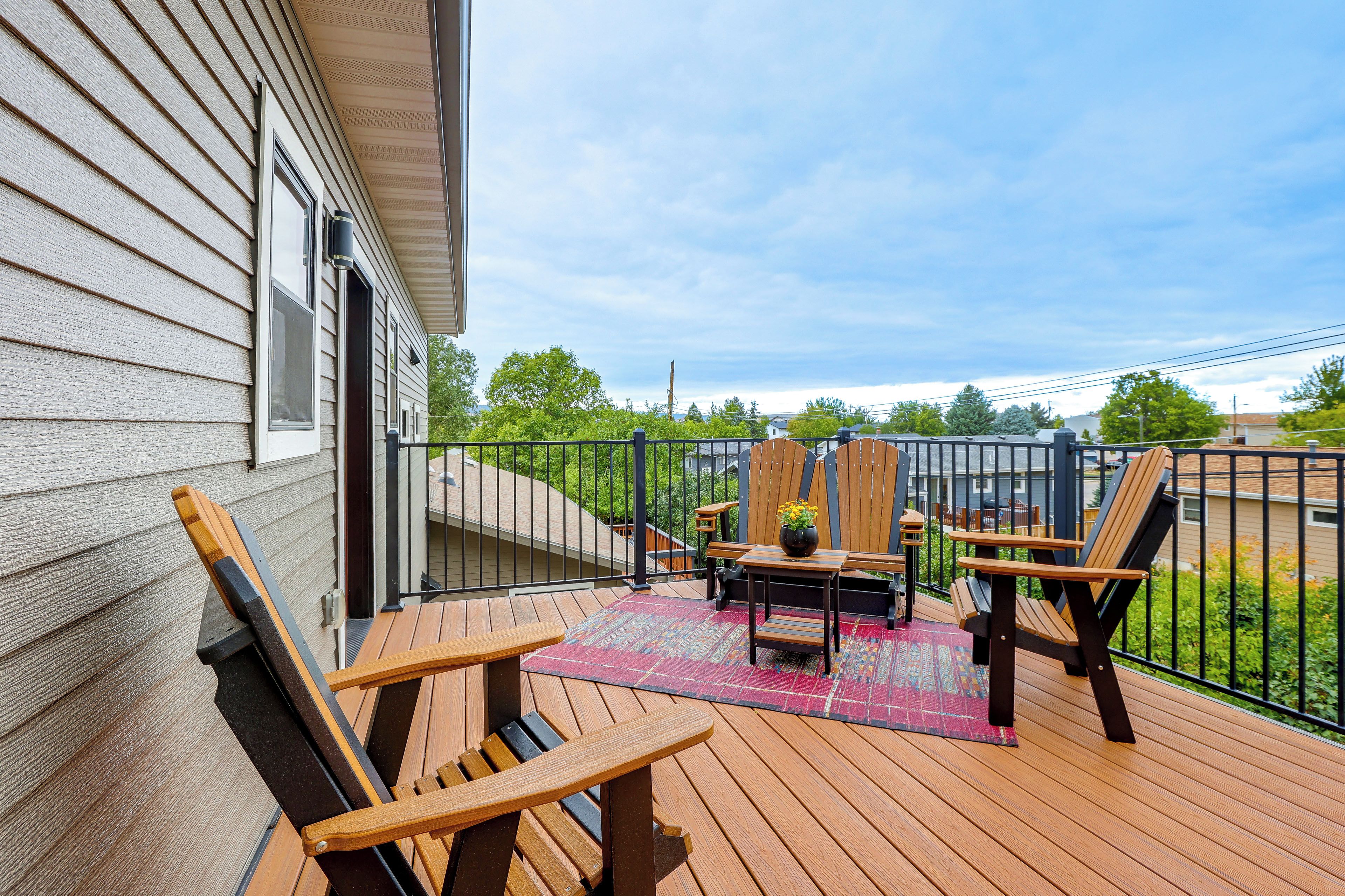 A wooden deck with outdoor furniture, a small table, and a rug.