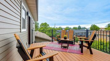 A wooden deck with outdoor furniture, a small table, and a rug.