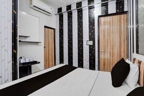 A hotel room with a bed, a bedside table with a kettle, and a wardrobe with a mirror. - Hotel O Sector 121 Gaur City Mall Noida (Noida)