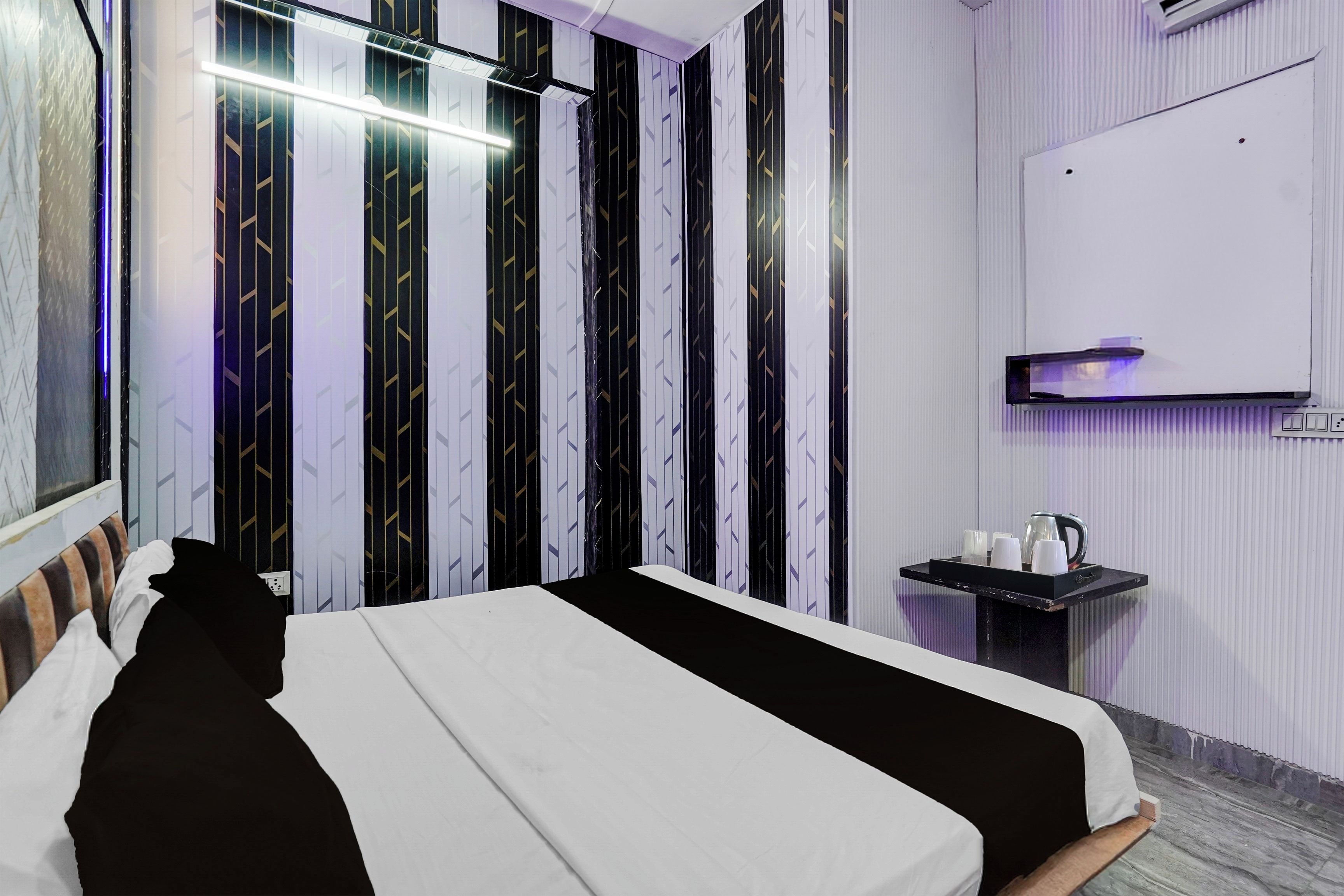 Ett modernt hotellrum med en stor säng, ett sängbord, en väggmonterad TV och ett fönster med utsikt.