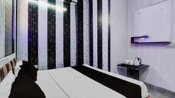 Ett modernt hotellrum med en stor säng, ett sängbord, en väggmonterad TV och ett fönster med utsikt.