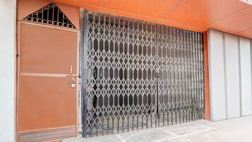 A metal gate with a diamond-patterned design, a brown door with a lock, and a tiled floor.