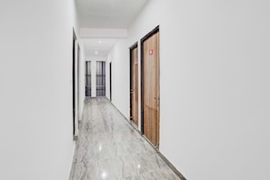 A corridor with a marble floor leading to a door marked with the number 209. - Hotel O Sector 121 Gaur City Mall Noida (Noida)