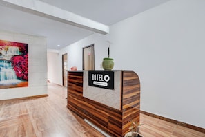 A hotel reception desk with a sign indicating it is company-serviced. - Hotel O Sector 121 Gaur City Mall Noida (Noida)