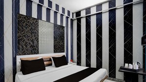 Un dormitorio moderno con una cama grande, cabecera de madera y un estampado a rayas blanco y negro.