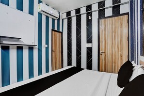 A hotel room with a bed, a wardrobe, and an air conditioning unit. - Hotel O Sector 121 Gaur City Mall Noida (Noida)
