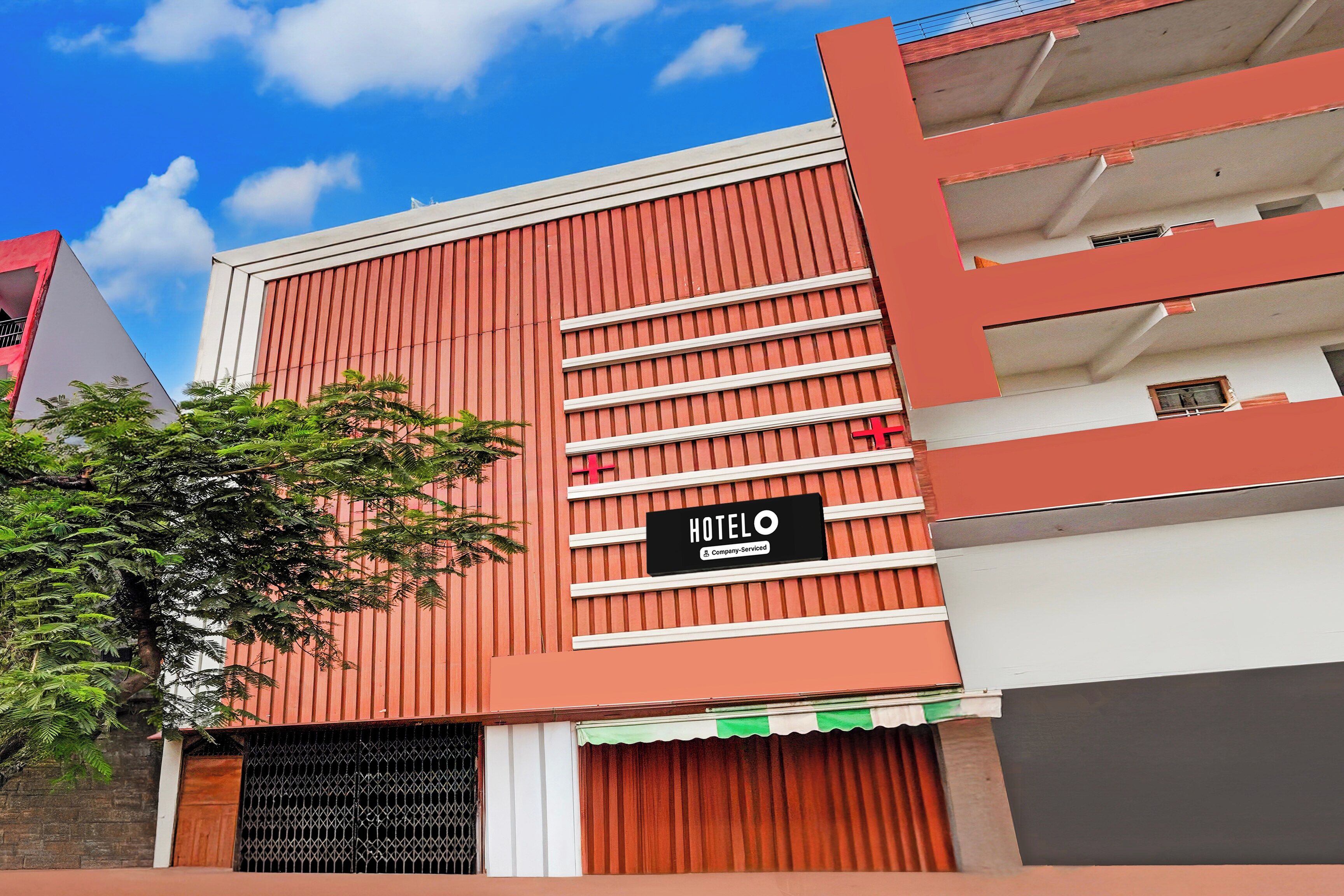 Un hotel con fachada roja, un letrero que indica servicio de empresa y una entrada con reja.