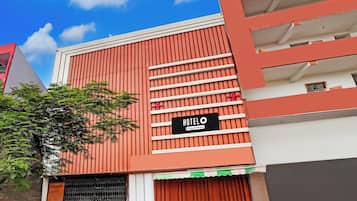 Un hotel con fachada roja, un letrero que indica servicio de empresa y una entrada con reja.