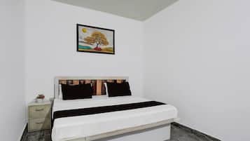 Un dormitorio con una cama, una mesita de noche, un cuadro enmarcado en la pared y un piso de mármol.