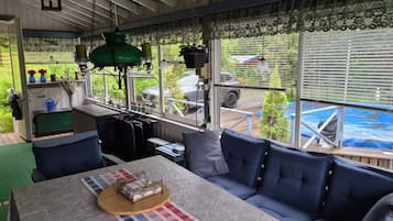 A cozy room with a sofa, a table, and a view of a car and greenery outside.