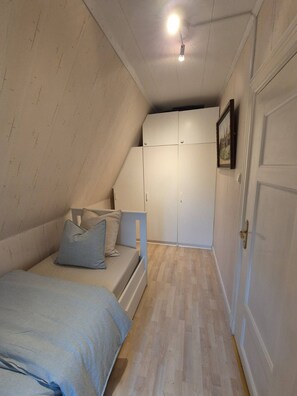 A bedroom with a bed, a wardrobe, and a door.