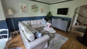 A living room with a sofa, a coffee table, a TV, and a staircase leading to another room.