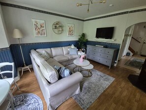A living room with a sofa, a coffee table, a TV, and a staircase leading to another room.